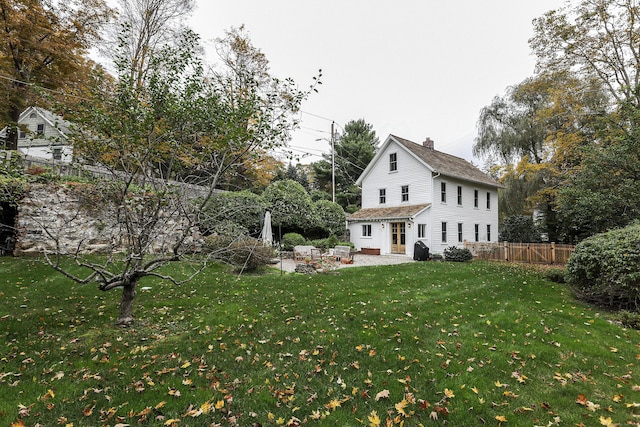 exterior space with a patio area, fence, a chimney, and a front lawn