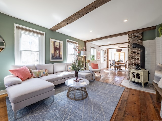 living area featuring recessed lighting, wood-type flooring, beam ceiling, and a wood stove