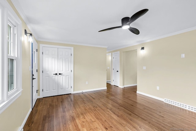 empty room featuring ornamental molding, wood finished floors, and baseboards