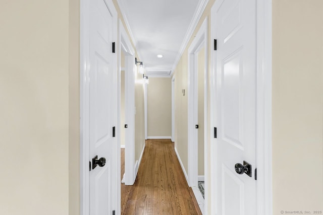 corridor featuring crown molding, baseboards, and wood finished floors