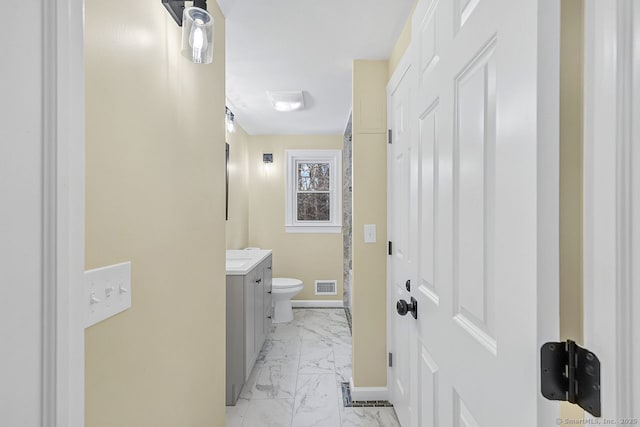 bathroom with toilet, vanity, visible vents, baseboards, and marble finish floor