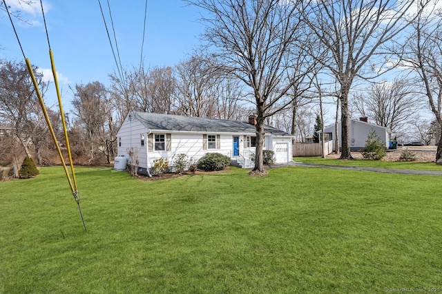 view of front of home with aphalt driveway, a front yard, a chimney, and an attached garage