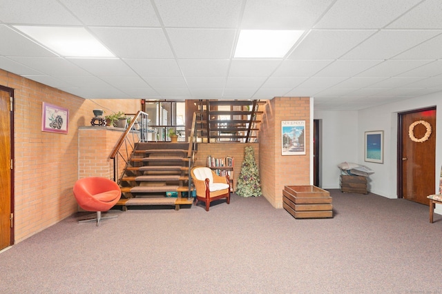 sitting room featuring brick wall, carpet, and a paneled ceiling