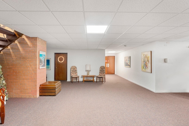 living area featuring carpet, baseboards, and a drop ceiling