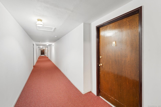 hall featuring carpet, attic access, and baseboards