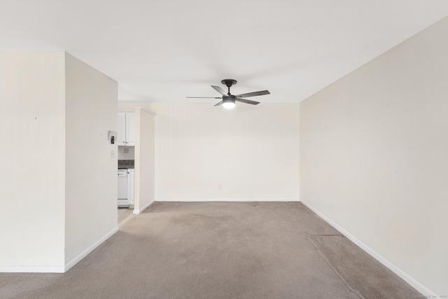 spare room with light carpet, ceiling fan, and baseboards