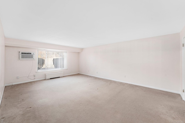 spare room featuring a wall unit AC, baseboards, and carpet flooring