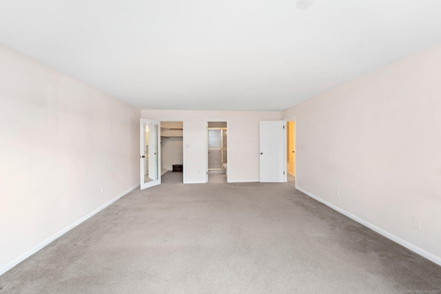 unfurnished bedroom featuring carpet floors, baseboards, and a walk in closet