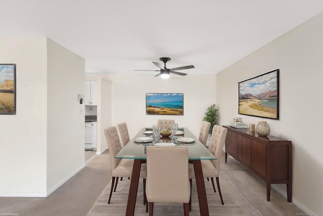 dining room with light colored carpet, ceiling fan, and baseboards