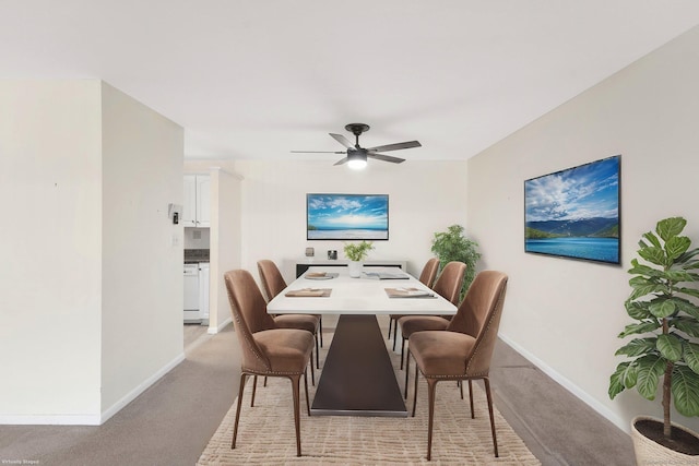 dining area featuring light carpet, ceiling fan, and baseboards