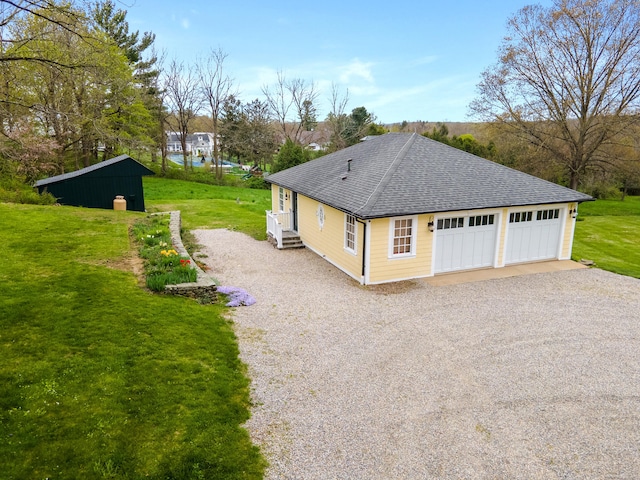 view of side of property with a garage, a yard, a shingled roof, and driveway