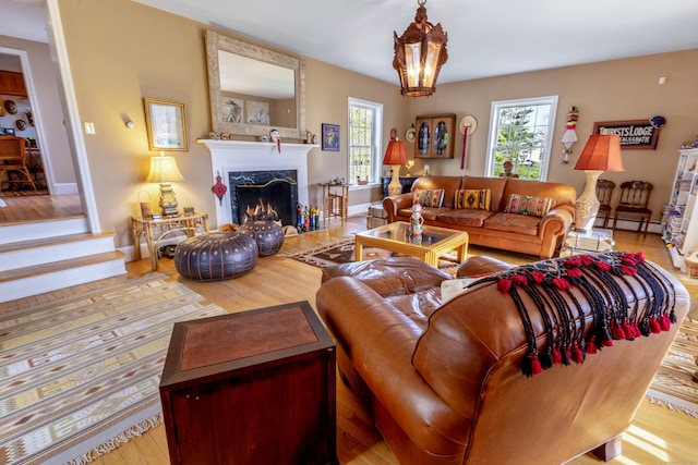 living room with wood finished floors, plenty of natural light, a fireplace, and a baseboard radiator