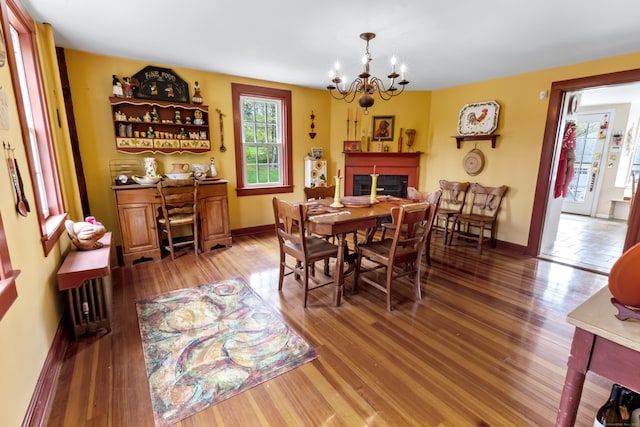 dining space featuring a chandelier, a glass covered fireplace, baseboards, and light wood finished floors