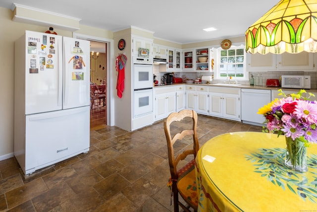 kitchen featuring stone finish flooring, white appliances, backsplash, and under cabinet range hood