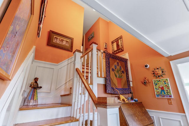 stairs with a wainscoted wall and a decorative wall