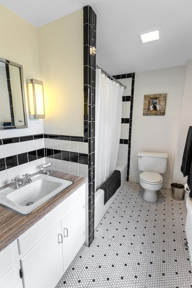 bathroom featuring toilet, tile patterned floors, shower / bath combination with curtain, and vanity