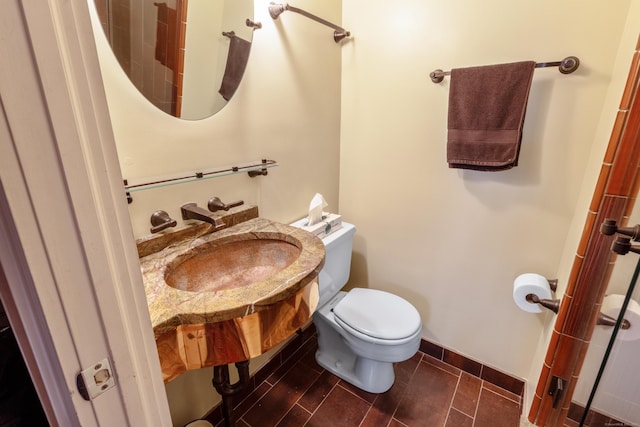 bathroom with a sink, toilet, and baseboards