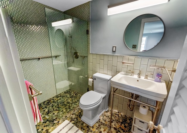 full bath featuring toilet, a shower stall, tile walls, and wainscoting