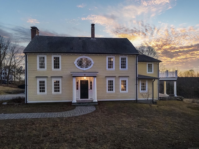 colonial-style house with a chimney and a front yard