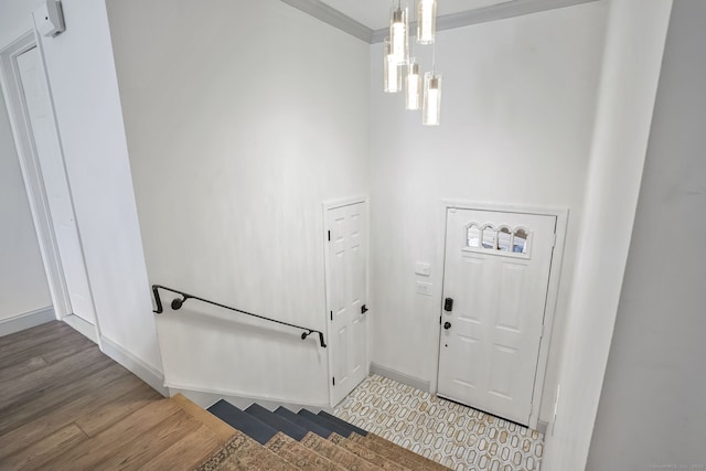 foyer with baseboards, crown molding, and wood finished floors