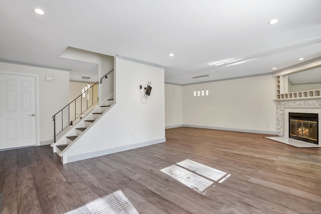 unfurnished living room with recessed lighting, a fireplace, wood finished floors, baseboards, and stairs