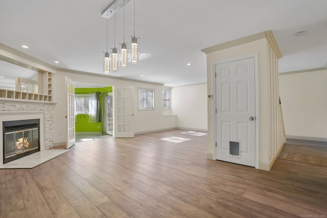 unfurnished living room featuring crown molding, recessed lighting, a glass covered fireplace, wood finished floors, and baseboards