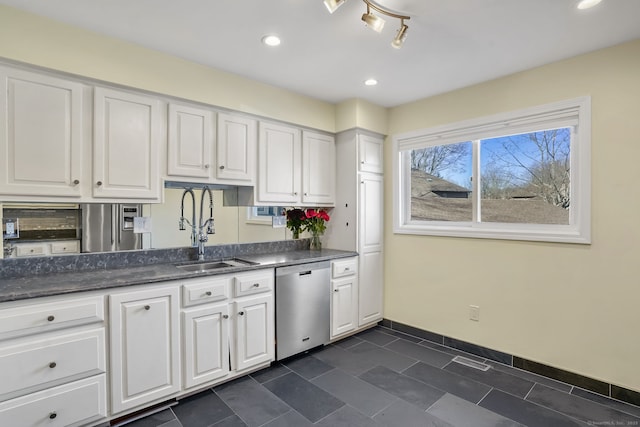 kitchen with baseboards, white cabinets, dishwasher, and a sink