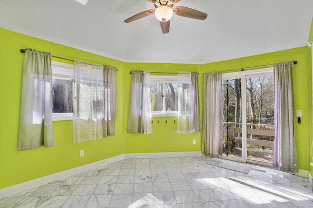 empty room featuring marble finish floor, ceiling fan, and baseboards