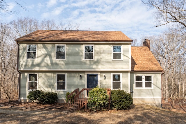 colonial-style house with a shingled roof and a chimney