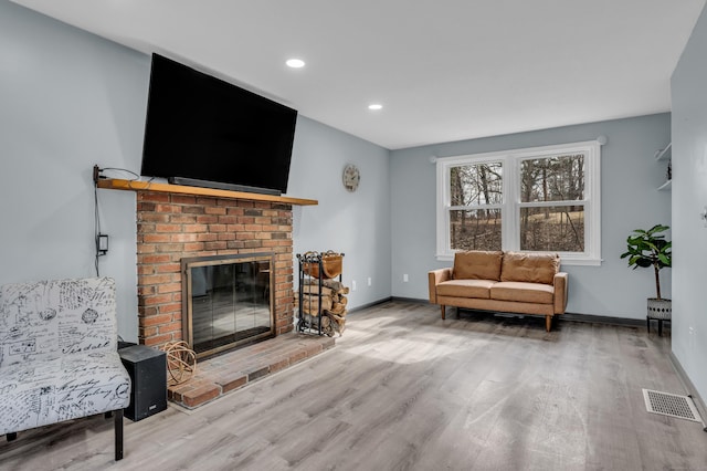 living area with a fireplace, recessed lighting, visible vents, wood finished floors, and baseboards