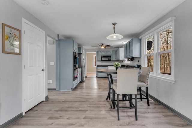 dining area featuring light wood-type flooring, baseboards, and a ceiling fan