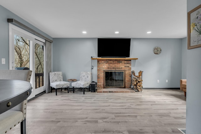 living area with recessed lighting, a brick fireplace, baseboards, and wood finished floors