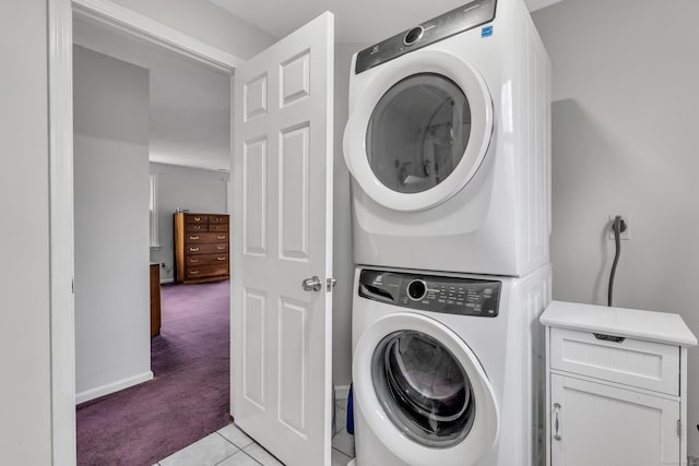 clothes washing area with light carpet, stacked washer and dryer, and light tile patterned floors