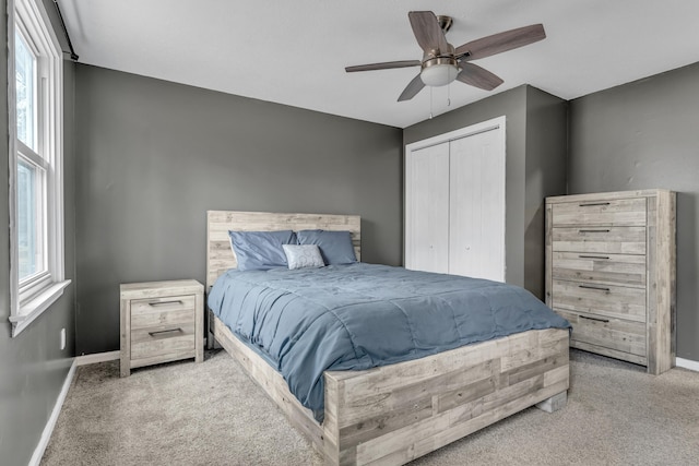 carpeted bedroom with a closet, multiple windows, and baseboards