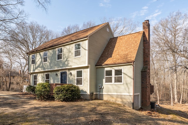 colonial inspired home with roof with shingles and a chimney