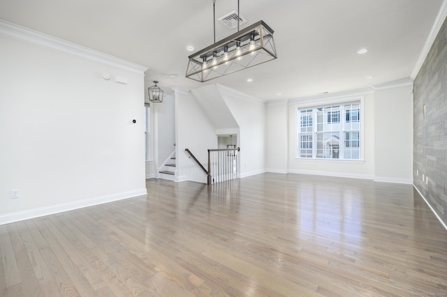 unfurnished living room with visible vents, wood finished floors, baseboards, and ornamental molding