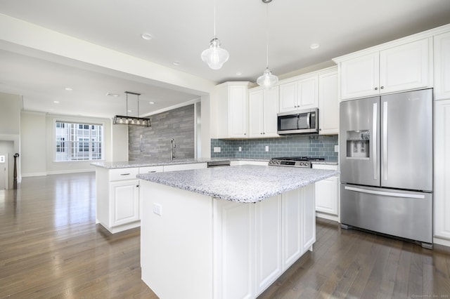 kitchen featuring tasteful backsplash, a center island, stainless steel appliances, white cabinets, and dark wood-style flooring