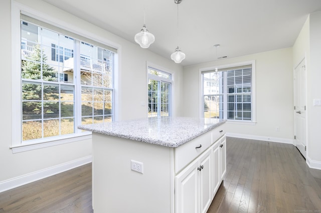 kitchen featuring hanging light fixtures, light stone countertops, dark wood-style flooring, and baseboards