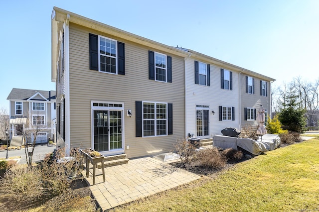 rear view of property featuring a lawn, entry steps, and a patio area