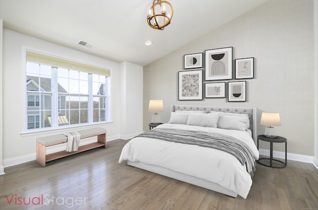 bedroom with lofted ceiling, wood finished floors, visible vents, and baseboards