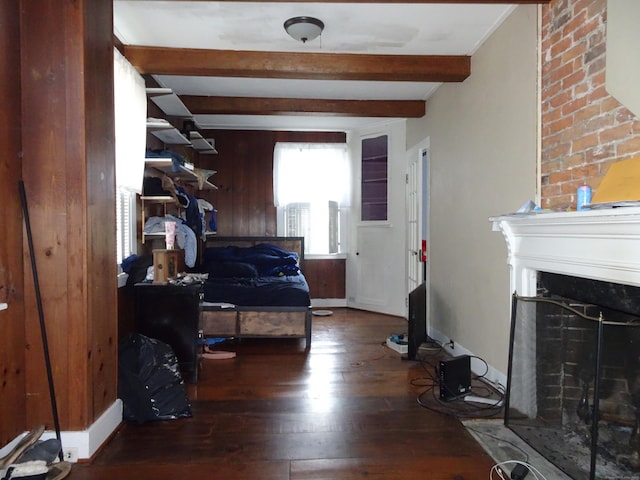 bedroom with hardwood / wood-style flooring, wood walls, a fireplace, baseboards, and beam ceiling