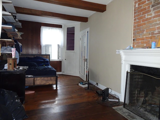 bedroom featuring hardwood / wood-style floors, a fireplace with flush hearth, baseboards, and beam ceiling