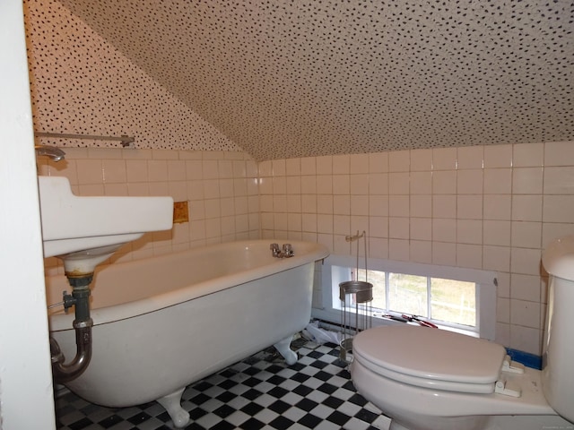 full bathroom featuring toilet, a freestanding bath, tile walls, and tile patterned floors