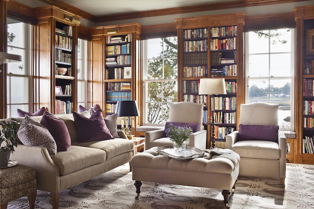 living area featuring crown molding, plenty of natural light, and wall of books