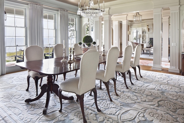 dining area with wood finished floors, ornate columns, and ornamental molding