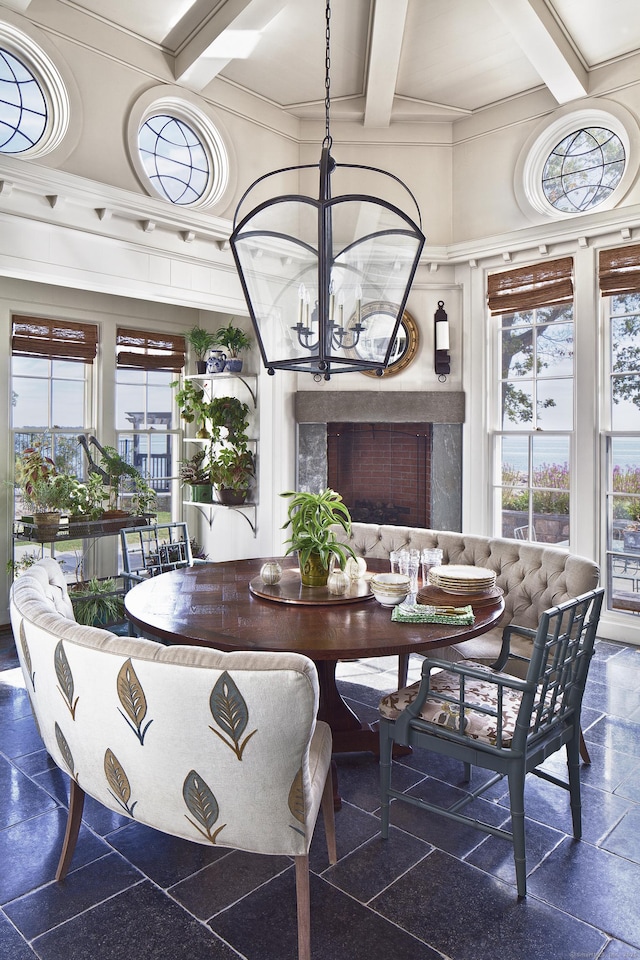 dining room featuring beam ceiling, coffered ceiling, a high end fireplace, granite finish floor, and an inviting chandelier