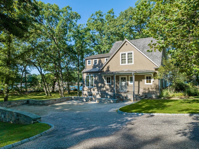 shingle-style home featuring driveway and a front lawn