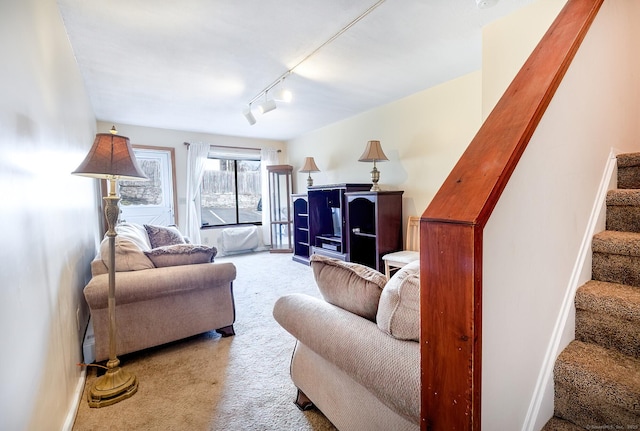 carpeted living area featuring rail lighting, baseboards, and stairs