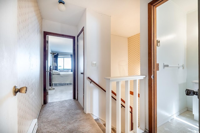 hall with light carpet, wallpapered walls, baseboards, and an upstairs landing