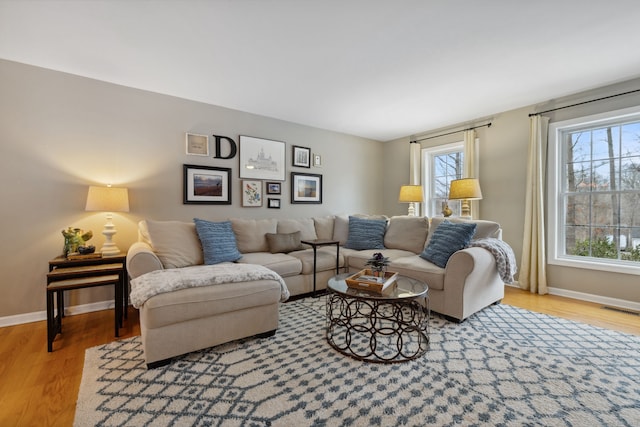 living area with baseboards, visible vents, and wood finished floors